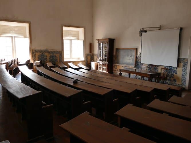 photo d'une salle de l'université de Coimbra au portugal avec des bancs anciens anciens