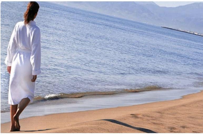 femme enpeignoir blanc marchant sur le sable