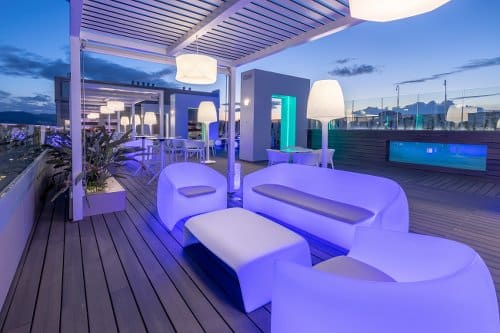 Photo de nuit de la terrasse d'un hôtel avec canapé et fauteuils blancs