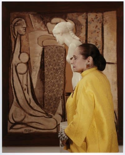 Helena Rubisntein photographiée avec un manteau jaune devant un tableau publiée dans le magazine les boomeuses